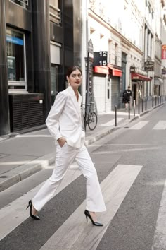 a woman in white is crossing the street