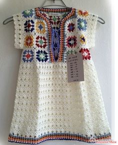 a white crocheted dress hanging on a wall with a price tag attached to it