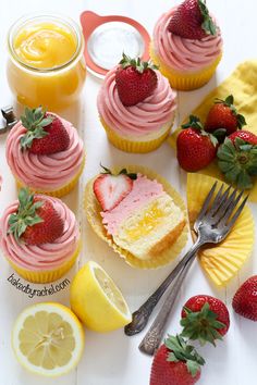 cupcakes with pink frosting, strawberries and lemon slices on the side