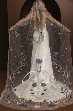 a woman in a white dress and veil with blue flowers on the skirt is holding a clock