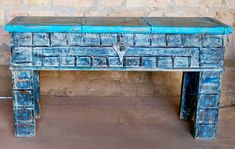 an old blue painted wooden table in front of a brick wall