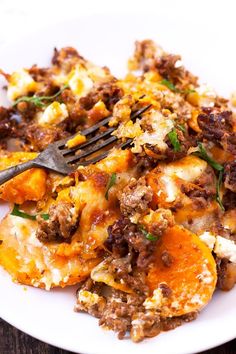 a close up of a plate of food with meat and cheese on it next to a fork