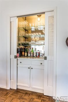 a bar with many bottles and glasses on the top shelf in front of an open door