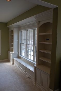 an empty room with bookshelves, cabinets and windows in the middle of it