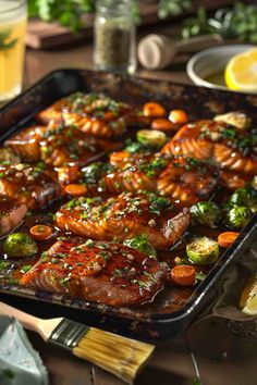 a pan filled with meat and vegetables on top of a table next to lemons