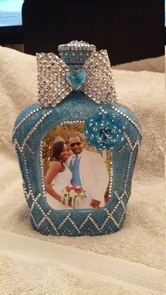 a blue bottle that has a picture on it with a bow around the top and diamond decorations at the bottom