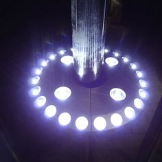 a circular fountain with many lit candles in the center and water spouting from it