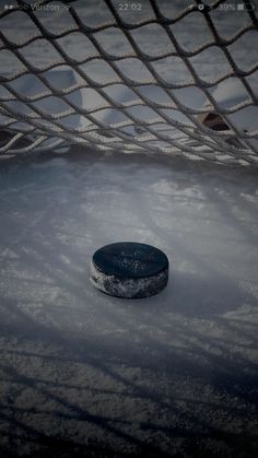 an ice hockey puck sitting on top of snow covered ground next to a goalie net