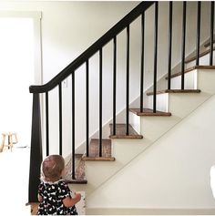 a toddler sitting on the floor in front of a stair case next to a set of stairs