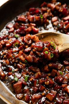 a wooden spoon in a pan filled with food