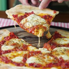 a person is cutting into a pizza with cheese and tomato sauce on the crusts