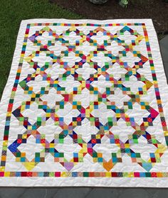 a multicolored quilt sitting on top of a stone walkway next to a potted plant