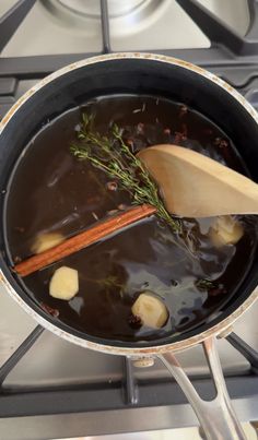 a wooden spoon in a pot filled with liquid and vegetables on top of a stove