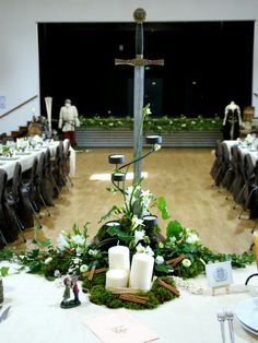 a centerpiece with candles and greenery is displayed on a table in a banquet hall