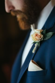 a man in a blue suit with a white flower on his lapel and a boutonniere