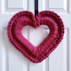 a knitted heart hanging on a white door