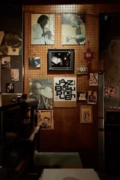 a wall with pictures and posters on it in a room filled with other things,