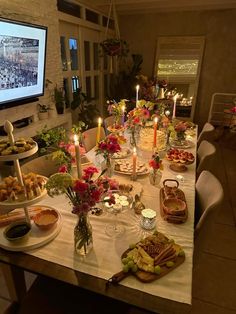 a table is set up with food and candles for a party or gathering in front of a tv