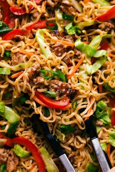 someone holding tongs over noodles with meat and vegetables