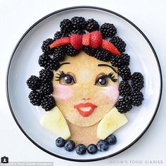 a white plate topped with fruit and a woman's face made out of pancakes