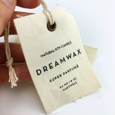 a hand holding a tag that says, natural soy candle dream wax super parfume