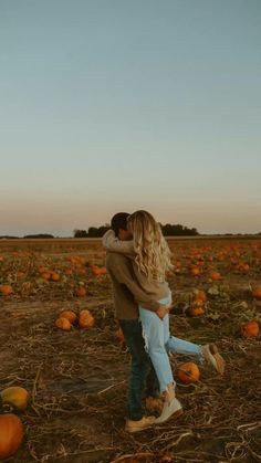 a man and woman embracing in a pumpkin patch