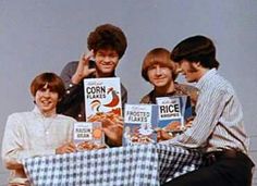 four people sitting at a table with boxes of cereal