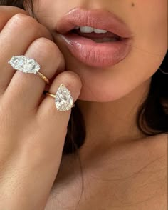 a woman wearing an engagement ring with two pear shaped diamonds