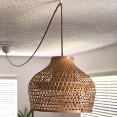 a wooden light hanging from the ceiling in a living room with blinds on the windowsill