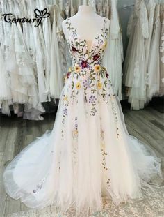 a white dress with flowers on it is displayed in front of other wedding gowns