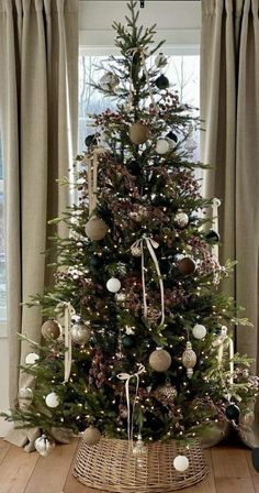 a small christmas tree with ornaments on it in the corner of a living room next to a window