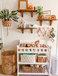 a white crib with baskets and plants on the wall next to it is filled with items