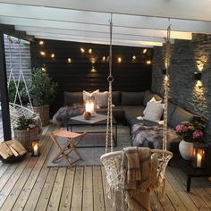 an outdoor living area with hammock chairs and lights on the ceiling, surrounded by wood flooring