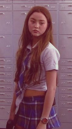 a girl standing in front of lockers with her hand on her hip and looking at the camera