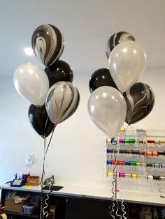 some black and white balloons are hanging from the ceiling in front of a shelf with markers