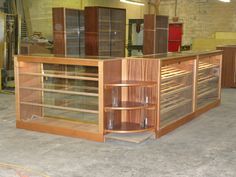 a large wooden counter with glass shelves in a room filled with other wood and glass items