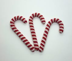 two red and white candy canes in the shape of a heart on a white surface