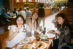 three women sitting at a table with plates of food and drinks in front of them