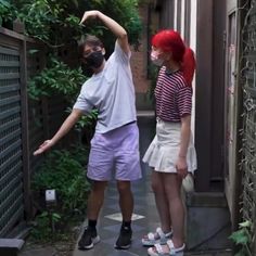 a man and woman wearing masks are standing in an alleyway with trees behind them