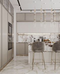 two gray chairs sitting at a bar in a kitchen with marble counter tops and white cabinets