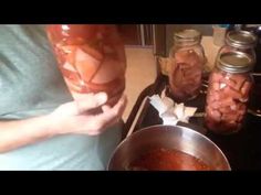 two jars filled with food sitting on top of a counter next to a person holding a spoon