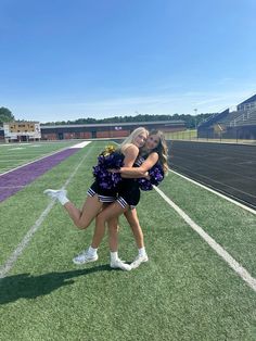 two cheerleaders hugging each other on the field