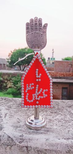 a red sign with a hand on it sitting on top of a stone wall in front of some buildings