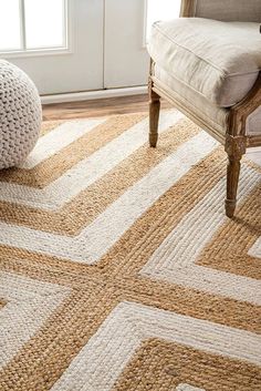 a chair sitting on top of a wooden floor next to a white and beige rug