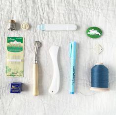 sewing supplies are laid out on a white sheet, including scissors, thread, and other items