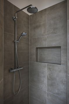 a shower head and hand held shower faucet in a bathroom with grey tiles