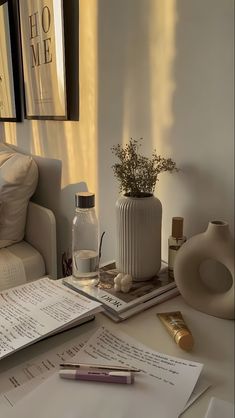 a table with papers, pens and vases on it next to a couch in a living room