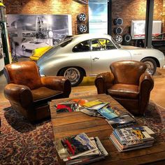 two chairs and a coffee table in a room with cars on the wall behind them