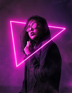 a woman wearing glasses standing in front of a neon triangle