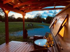 a covered patio with tables and chairs under a wooden pergolan roof at dusk